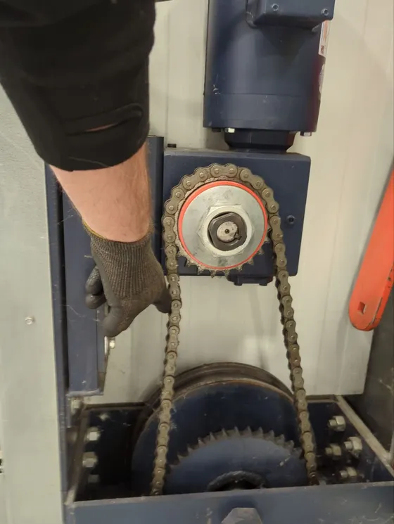 Technician servicing a hangar door motor chain drive