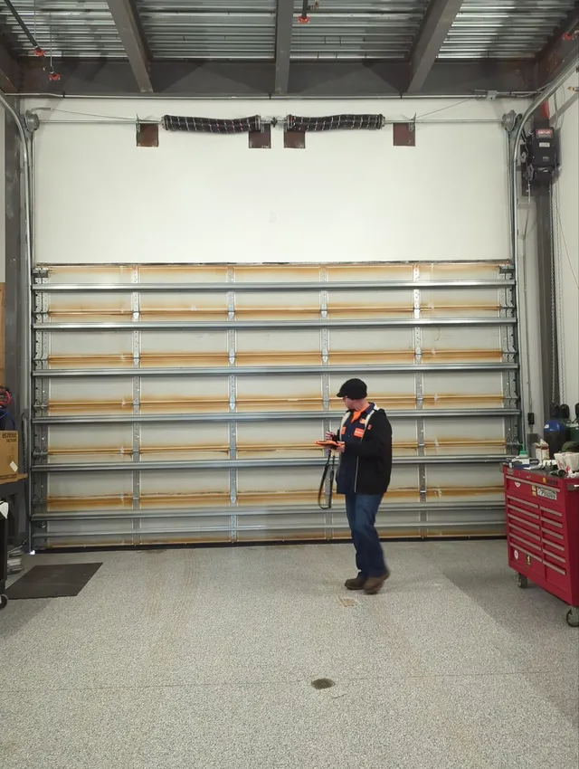 Technician performing a planned maintenance inspection on a sectional door